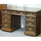 An Edwardian oak kneehole desk, fitted a surround of nine drawers,