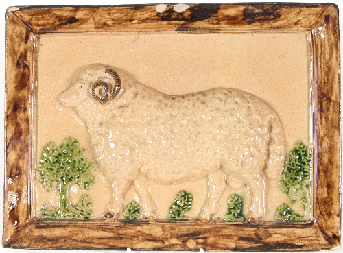 A Yorkshire lead-glazed earthenware plaque, moulded in relief with a ram in a pastoral setting,