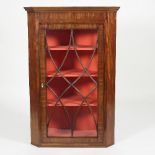 A George III mahogany corner cupboard enclosed by an astragal glazed panel door,