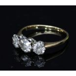 A three-stone diamond ring, the stones claw set to an unhallmarked yellow metal shank,