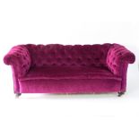 A two-seater button back Chesterfield sofa with mahogany turned front legs,