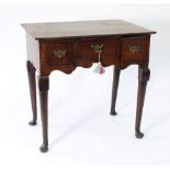 A George III oak lowboy, fitted three drawers above a shaped apron on tapering legs with pad feet,