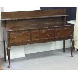 An oak dresser base of three drawers, with single shelf gallery back on front cabriole legs,