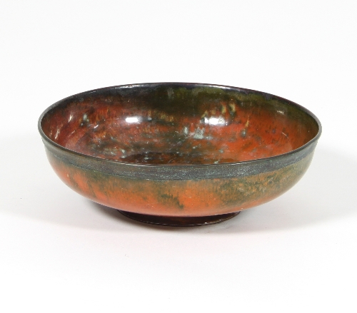 William Hair Haseler: An Arts and Crafts enamelled copper bowl in orange and mottled green on