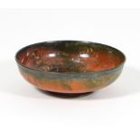 William Hair Haseler: An Arts and Crafts enamelled copper bowl in orange and mottled green on