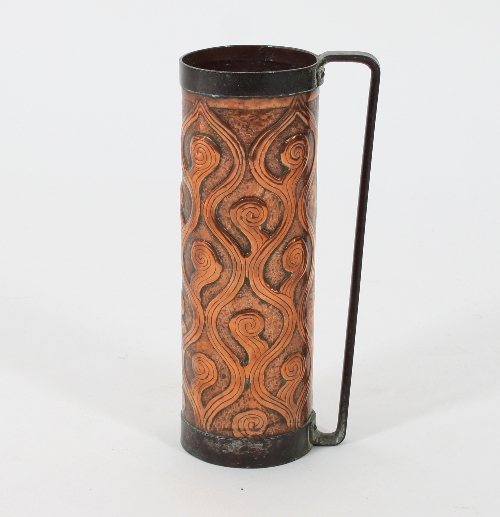 An Arts & Crafts copper wine bottle carrier of cylindrical form with embossed wave and scroll