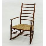 An Arts and Crafts style ladder back rocking chair with rush seat
