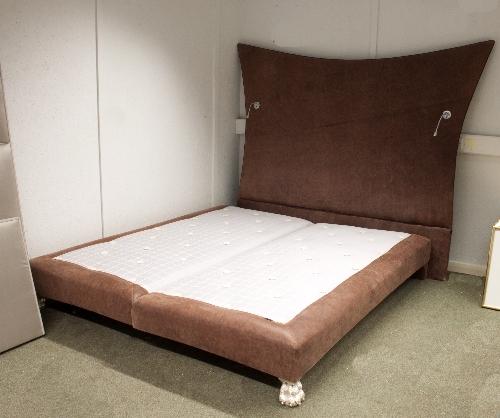 A six foot bed on silvered hairy paw feet together with a large brown leather upholstered headboard