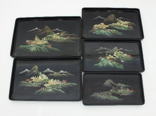 A graduated set of five Japanese lacquered trays, each painted with a rocky mountainous landscape,