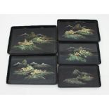 A graduated set of five Japanese lacquered trays, each painted with a rocky mountainous landscape,