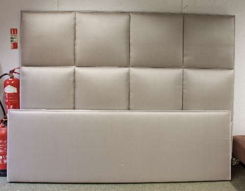 A large pale grey upholstered headboard with matching footboard,