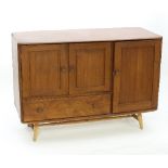 An Ercol elm sideboard, fitted a single panel door, a pair of panel doors and a single long drawer,