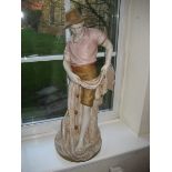 A large Royal Dux figure of a gentleman resting against a tree stump with throw in hand, pink