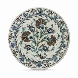 AN IZNIK POTTERY DISH OTTOMAN TURKEY, 17TH CENTURY Of circular form on short ring foot, with sloping