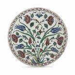 AN IZNIK RIMLESS POTTERY DISH OTTOMAN TURKEY, CIRCA 1580 Of circular form on short ring foot, the