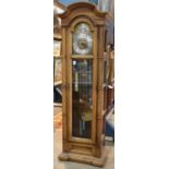 Howard Miller oak grandfather clock, having a molded top above an Arabic numeral dial, continuing to