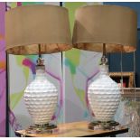 Pair of modern lamps with white baluster form standards, gold fabric covered shades and rising on