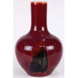 Chinese flambe glaze stickneck vase, with a mottled red exterior and dark patches, 13"h