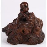 Chinese root wood carving, depicting a seated scholar with a contorted face having an item clasped