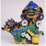 Chinese polychrome ceramic fu-lion, accented by flowers and with a ball below his foot (chips), 19"