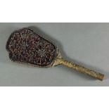 Chinese carved lacquer and brass hand held mirror, the shaped back with carved black peonies set