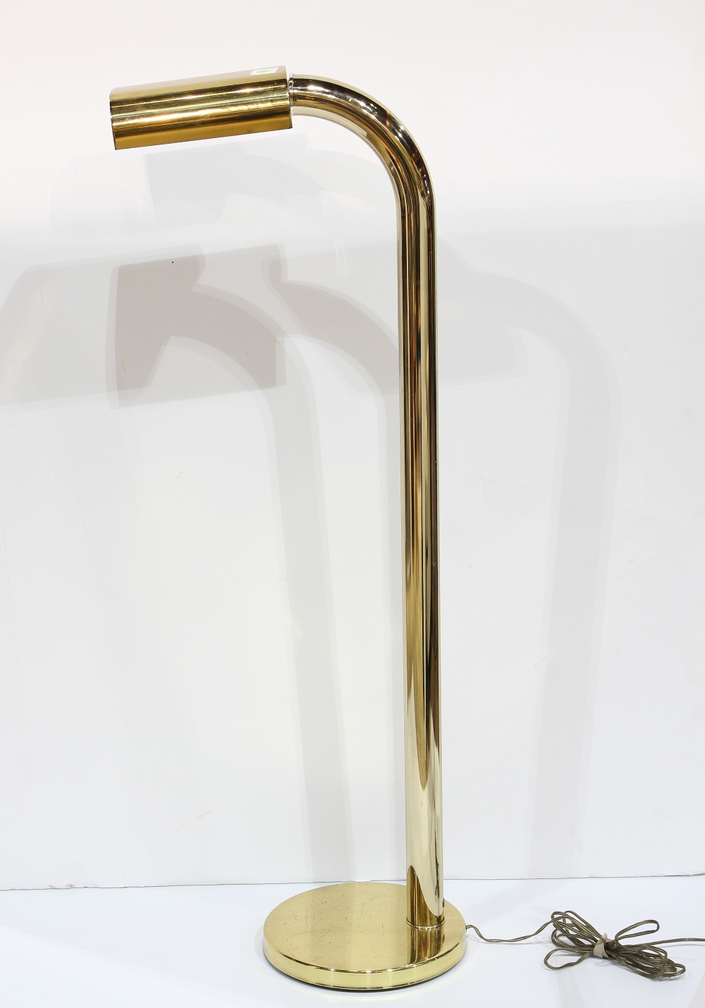 Moderne brass floor lamp, having a single arm suspended from the telescoping standard, and rising on