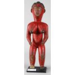 Guro, Ivory Coast red painted standing female figure with styled hair and naturalistic features, and