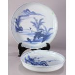 (lot of 2) Japanese large Arita blue-and-white deep dishes: one with a scene depicting shuro palms