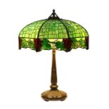 Handel patinated bronze and leaded glass table lamp, the domed shade having a grape pattern, above