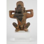 Pre-Columbian ceramic prisoner figure, depicting a squating figure, wearing a zoomorphic mask,