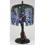 Tiffany style leaded glass and patinated bronze table lamp, the dome shade having wisteria flowers