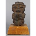 Pre-Columbian style volcanic stone figure in a hunkered posture mounted to wood plinth, possibly