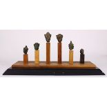 (lot of 6) Thai bronze Buddha heads, of various styles each with a benevolent face, on a wood stand,