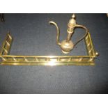 A polished brass fireside fender and an Indian brass ewer