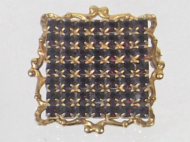 A Yellow Metal Brooch With Garnets