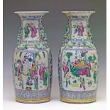 Pair of Chinese Famille Rose vases, each having two reserves showing an interior scene with figures,