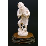 Japanese carved ivory okimono, Meiji period, formed as a man holding a stick and fruit in his