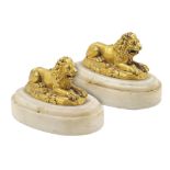 A pair of French gilt-bronze lions 18th century 8x12x8 cm. standing on oval Carrara marble bases