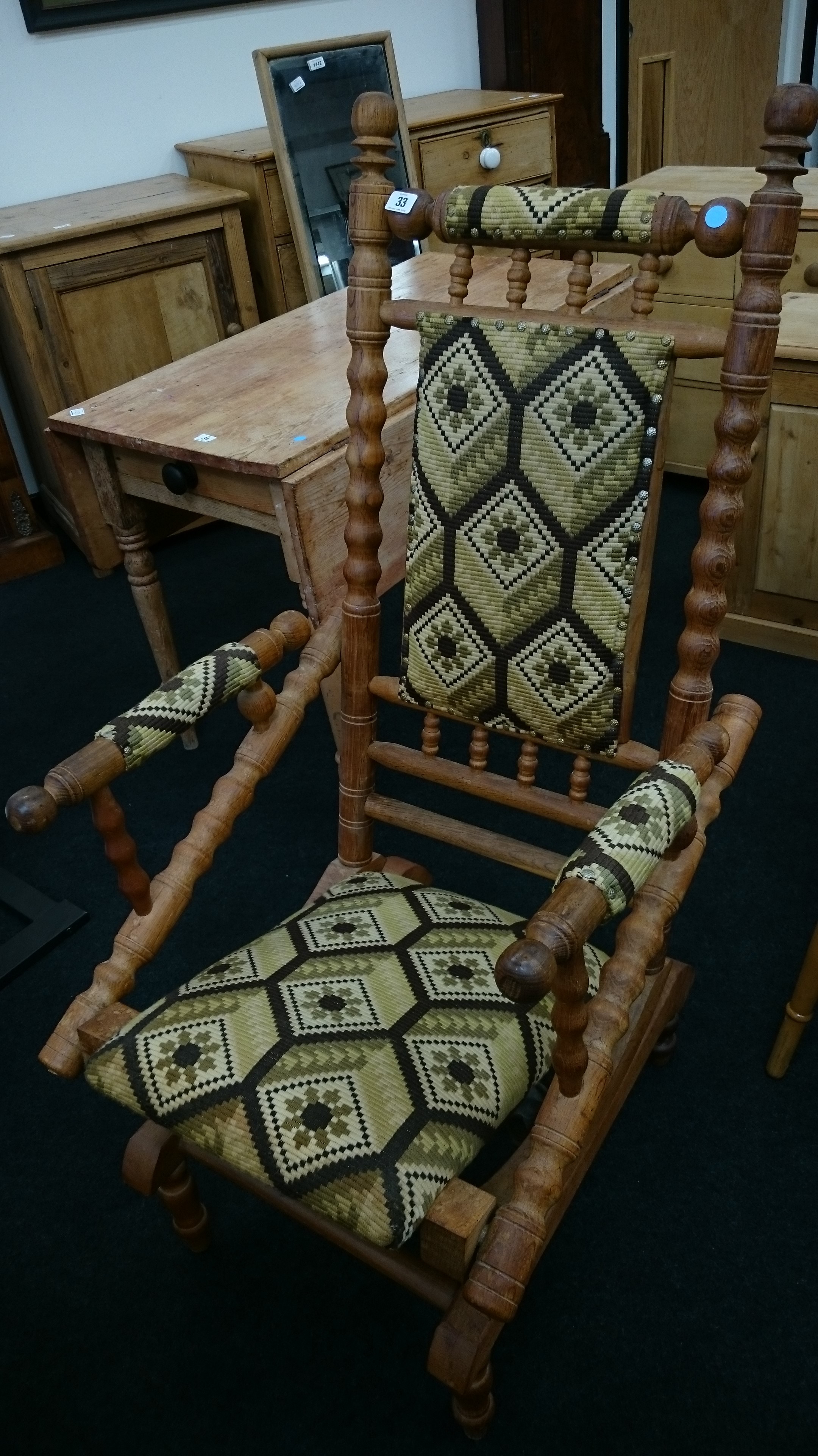 A large pitch pine American rocker with upholstered seat, back rest and arms.