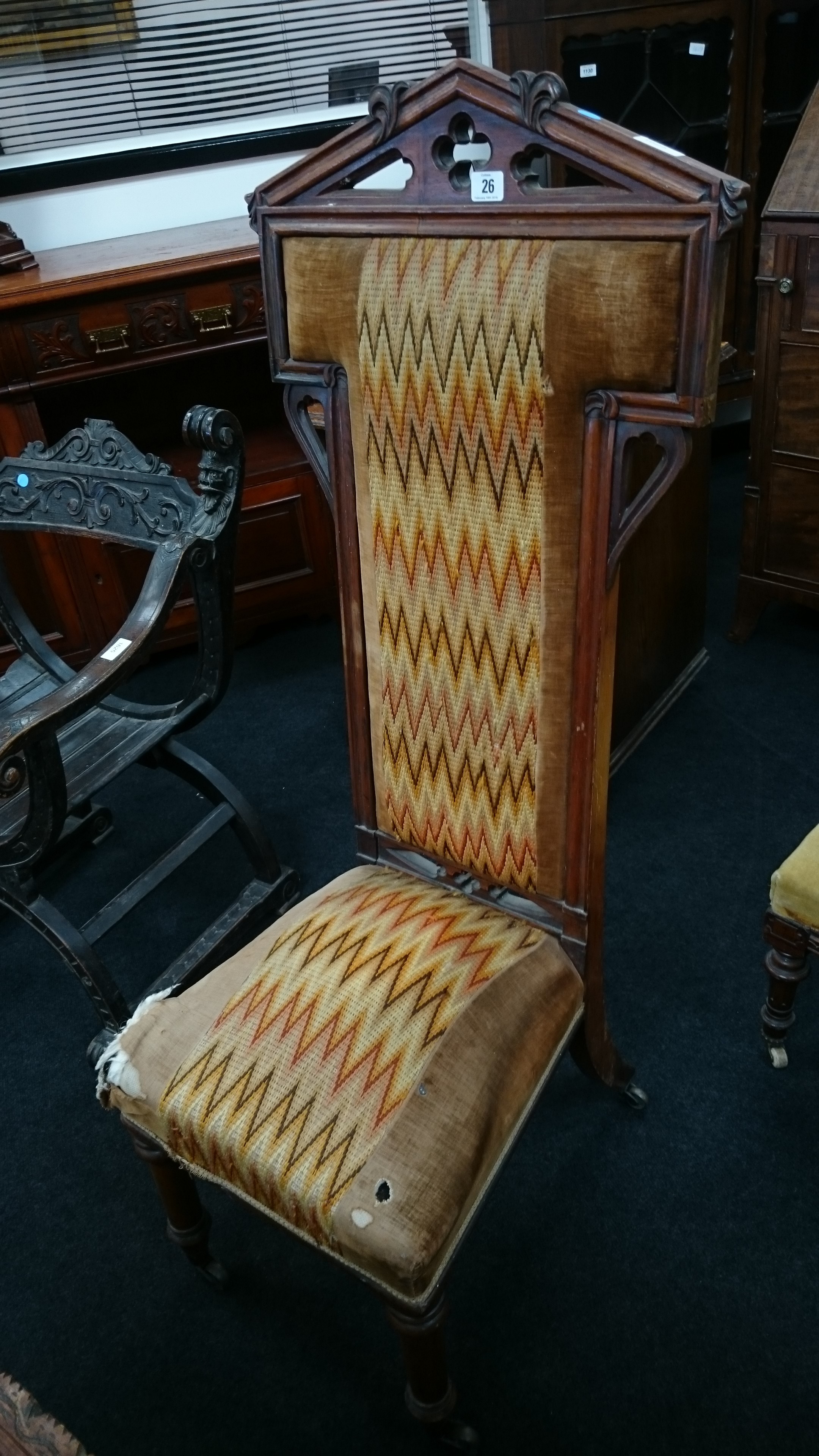 A mahogany framed upholstered prayer chair, resting on turned supports to front castors.