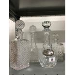 Four glass decanters together with a silver Vodka decanter label.
