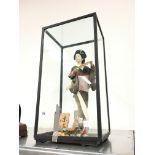A Japanese doll in glass display cabinet.
