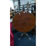 A mahogany snap-top tripod table resting on pad feet.