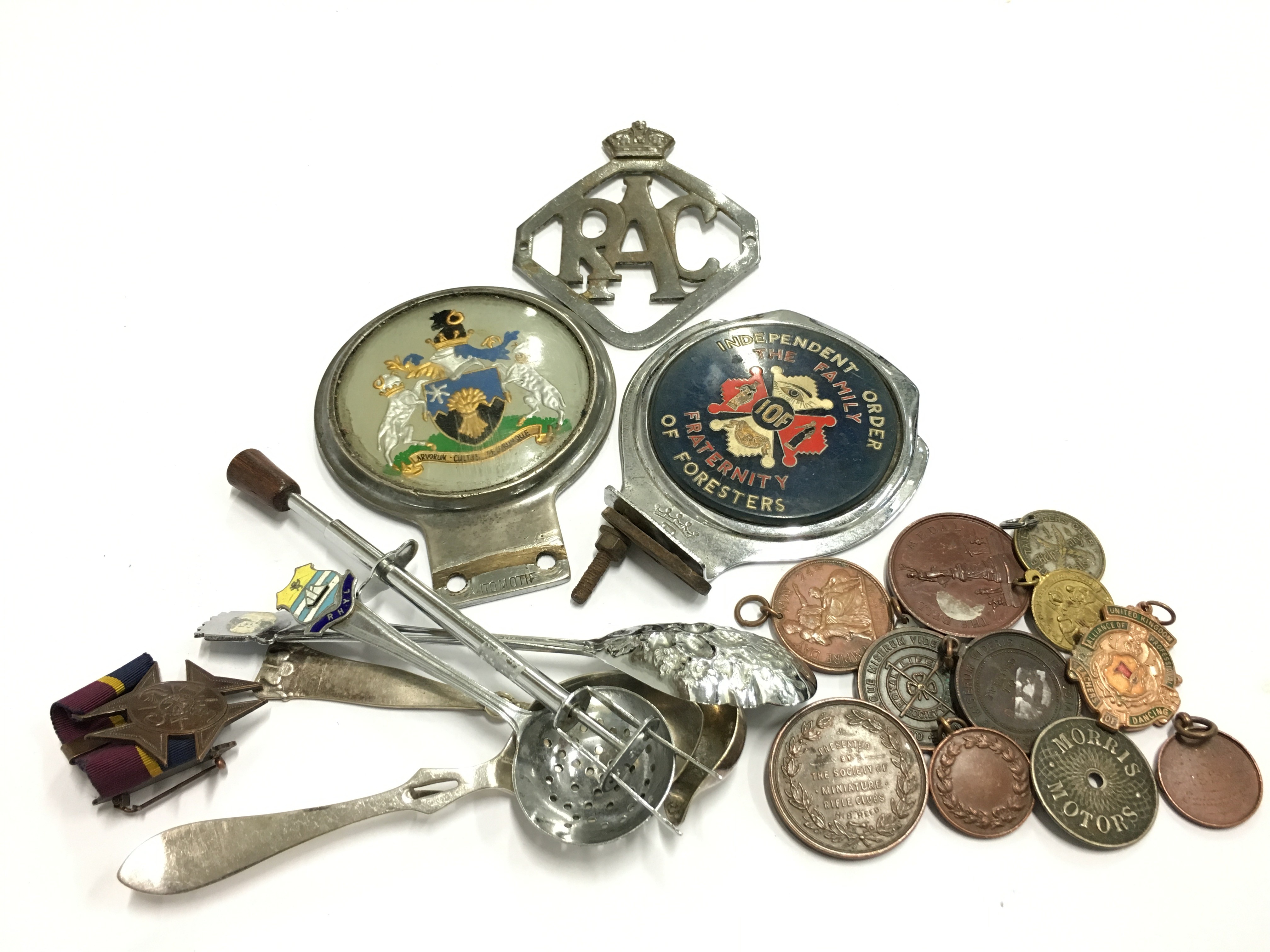 A carton containing three various car badges together with other items including medallions.