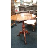 A mahogany drop flap tripod table with circular top.