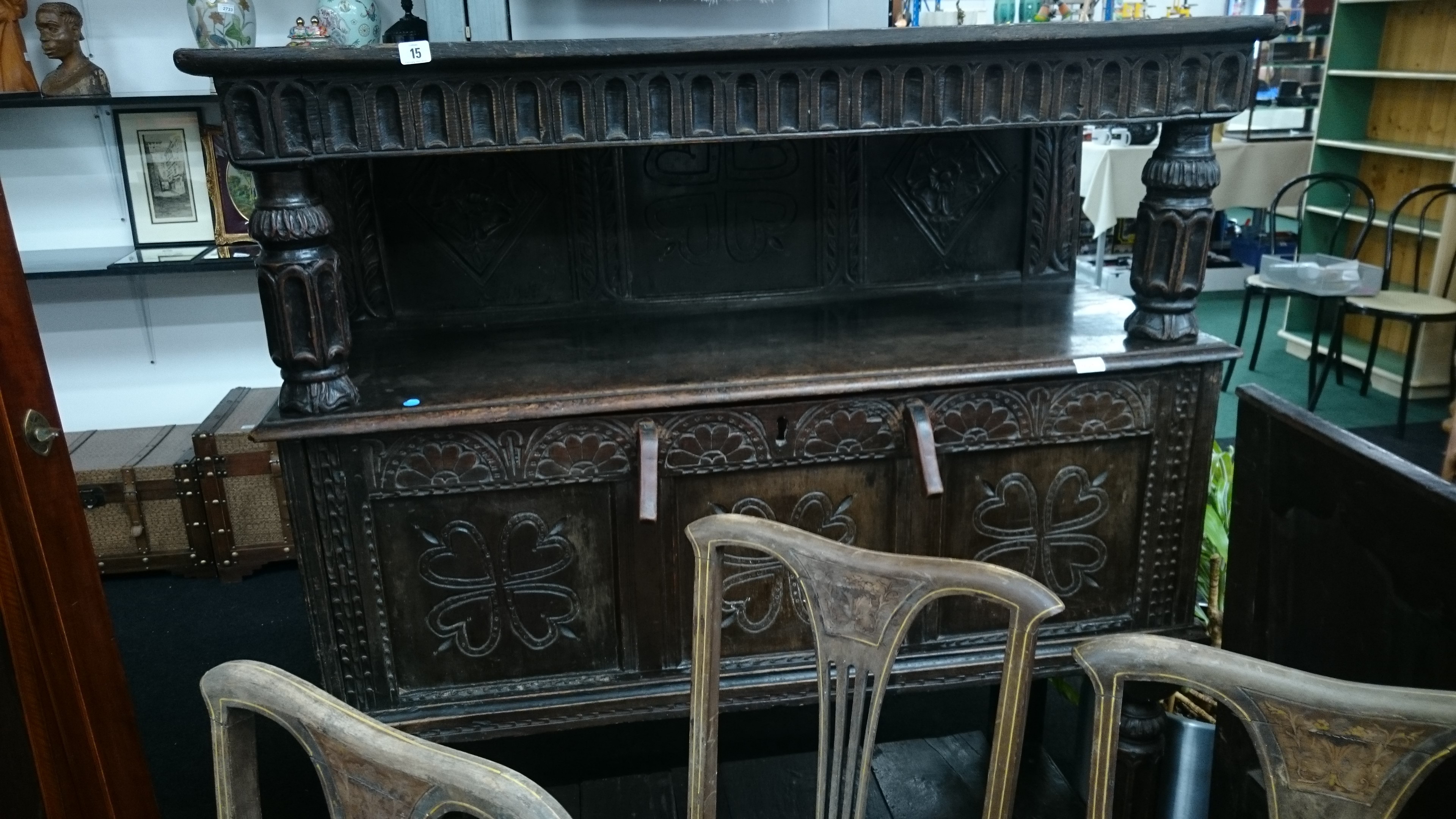 A large heavily carved three tier panelled court cupboard resting on decorative column supports.