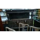 A large heavily carved three tier panelled court cupboard resting on decorative column supports.