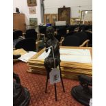 A reproduction Art Deco bronze modelled as a young woman applying make-up seated on a tall stool.