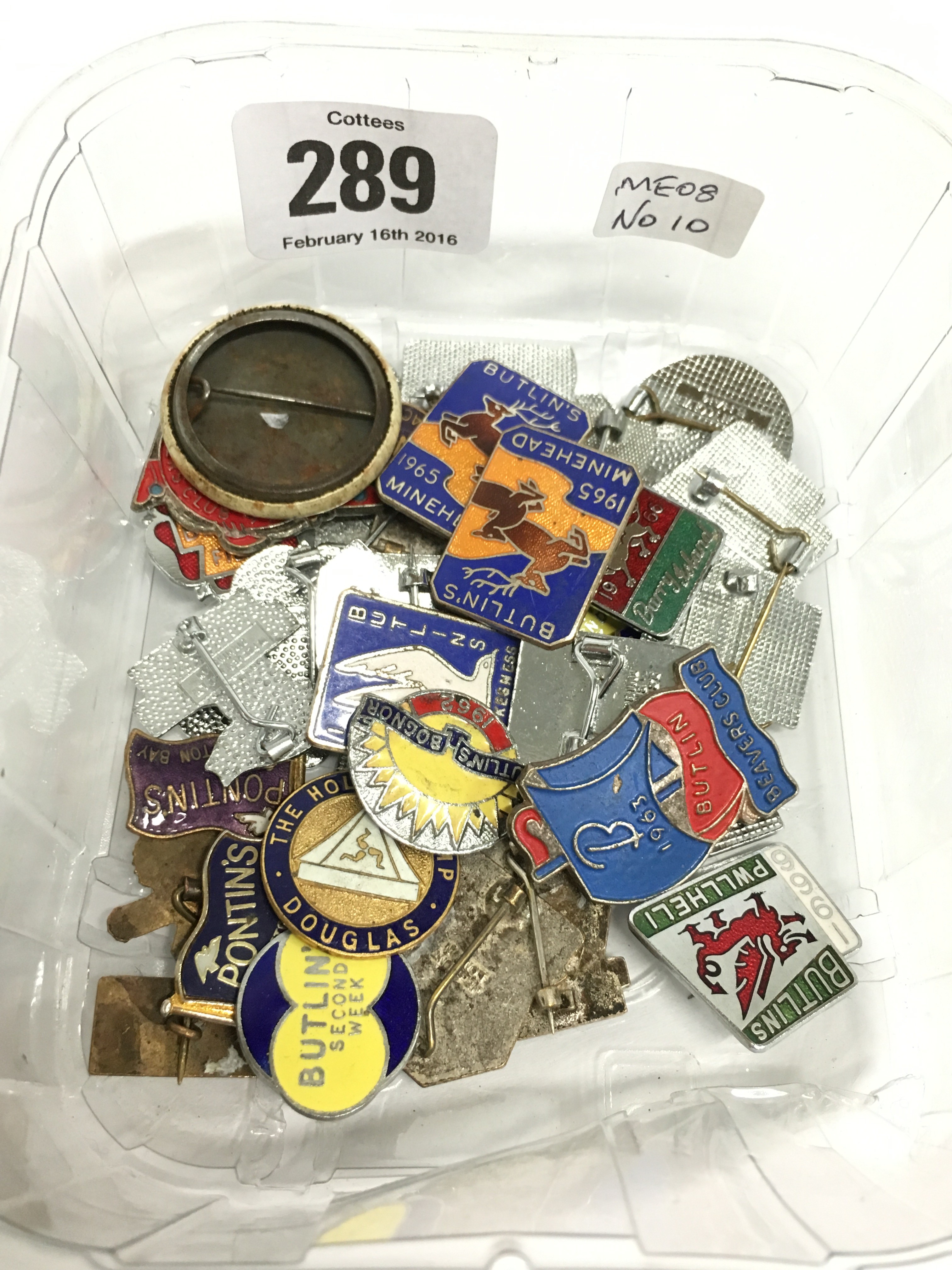A carton containing various Butlins souvenir badges.
