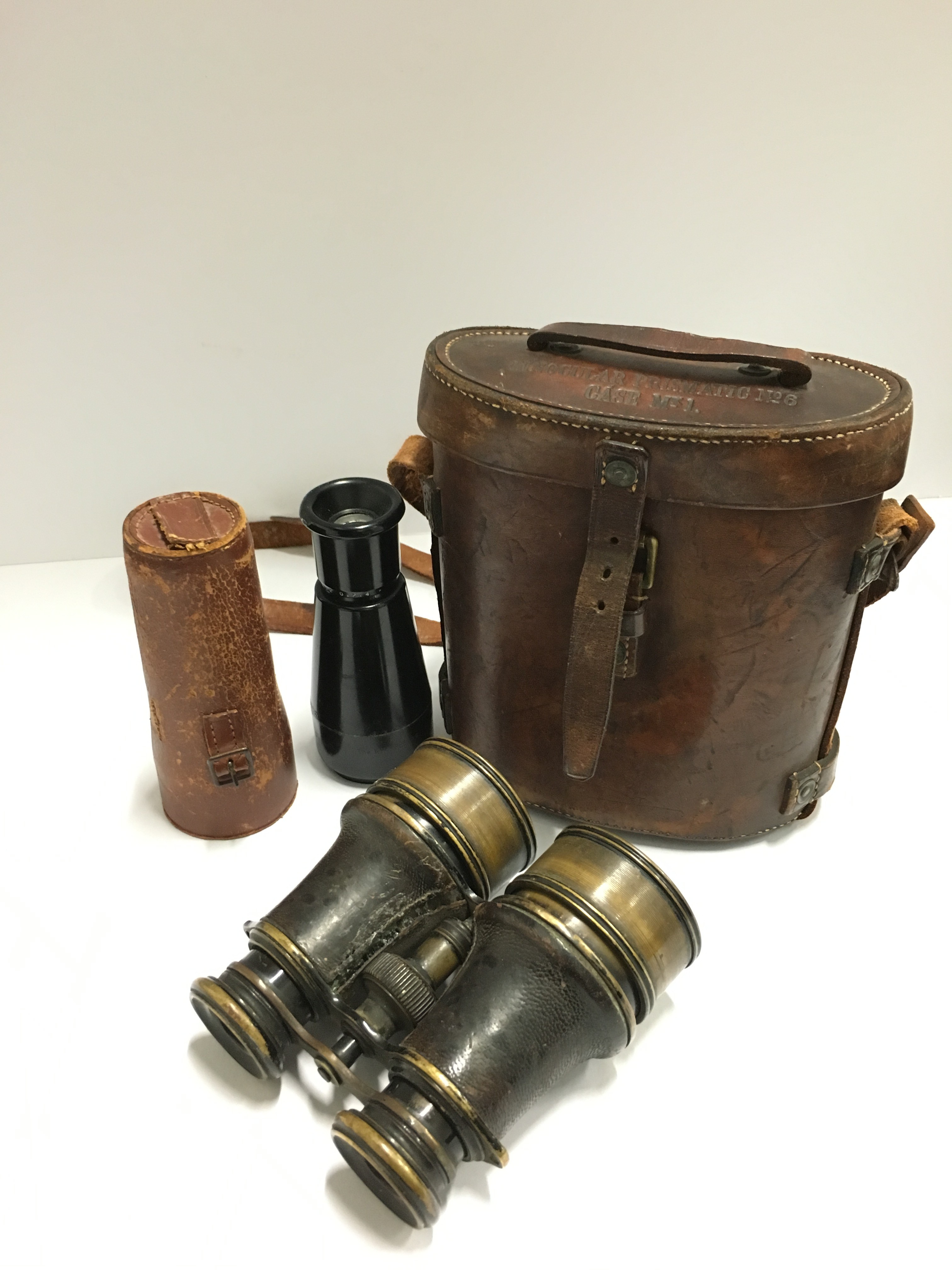 A pair of early 20th century binoculars together with a brown leather Military binocular case and a